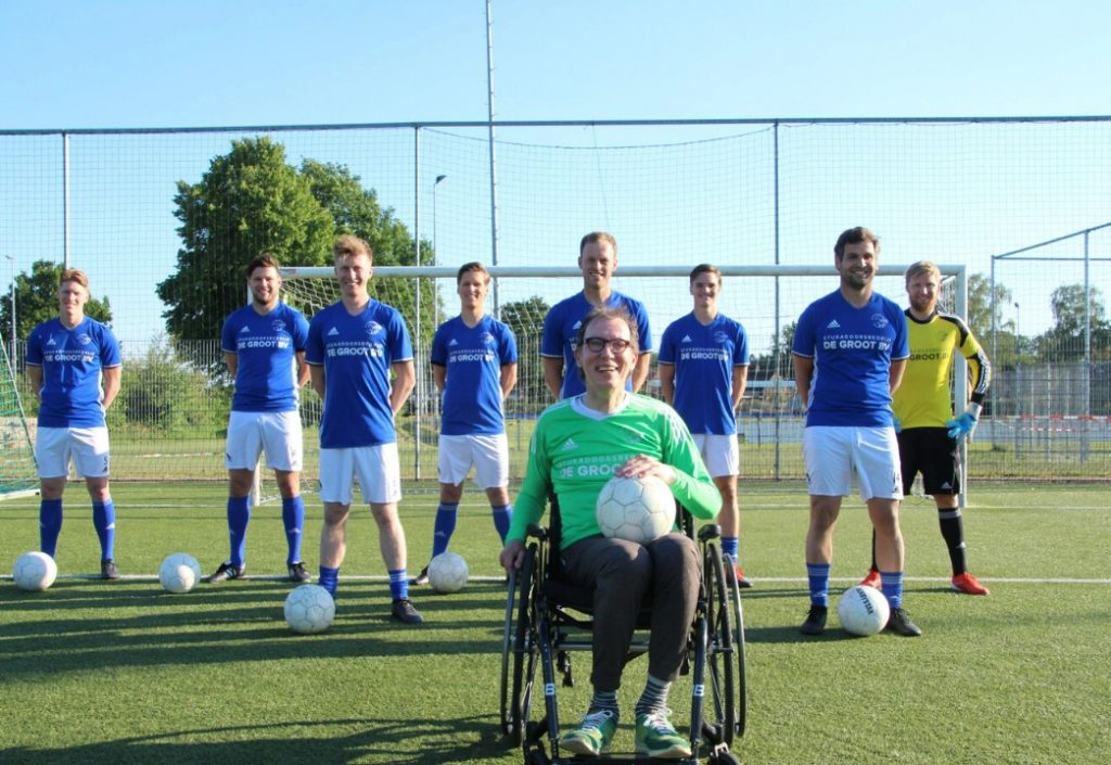 blije man in rolstoel bij voetbalteam